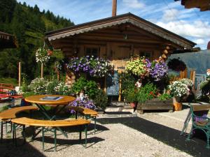 a wooden cabin with a table and chairs and flowers at Hütte Wilfried in Hainzenberg