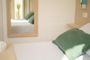 a green pillow sitting on a bed in front of a mirror at Viver Guest House in La Caletta +126 photos