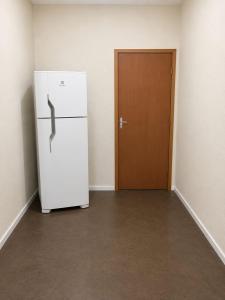 a white refrigerator in an empty room with a door at Pousada CTI in Taubaté