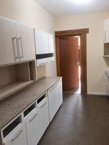 an empty kitchen with white cabinets and a door at Pousada CTI in Taubaté +8 photos