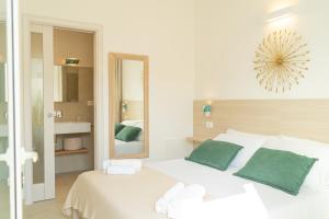 a white bedroom with a large white bed with green pillows at Viver Guest House in La Caletta