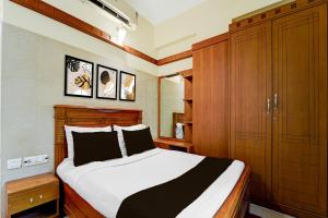 a bedroom with a bed and wooden cabinets at Hotel O Stay First in Coimbatore