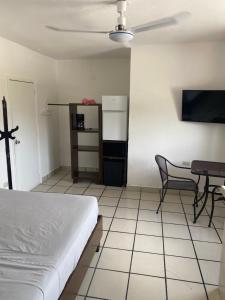a bedroom with a bed and a table and a refrigerator at Caribo Cozumel in Cozumel