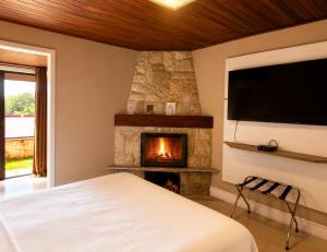 ein Schlafzimmer mit Kamin und Flachbildfernseher in der Unterkunft Hotel Willisau in Teresópolis