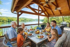 a family sitting around a table eating dinner on a deck at Ultimate Lake Norris Getaway with Private Dock in New Tazewell