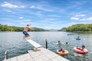a man jumping off a dock into a lake at Ultimate Lake Norris Getaway with Private Dock in New Tazewell