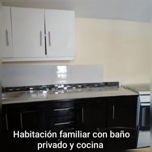 a kitchen with white cabinets and a black counter top at Hostal Atlantis Middle World in Quito