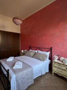 a bedroom with a bed and a red wall at La Maison D'Amì in Anguillara Sabazia