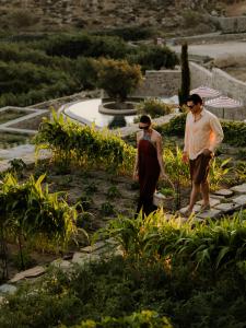 two men walking through a garden with plants at Tropicana Suites & Villas Mykonos in Paradise Beach