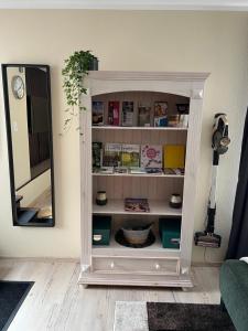 a white book shelf in a room with a mirror at Ferienwohnung Stoll - modern, mit Ausblick & Grill in Idar-Oberstein