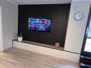 a room with a tv on a wall with a clock at Ferienwohnung Stoll - modern, mit Ausblick & Grill in Idar-Oberstein