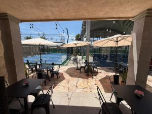 a patio with tables and umbrellas and a swimming pool at Hotel Camino Del Bosque Centro Pádel in Cholula