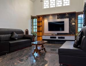 a living room with two couches and a flat screen tv at Bamivigas Retreat in Kattappana