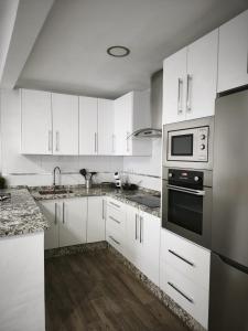 a white kitchen with white cabinets and appliances at Los Titos in Arriate