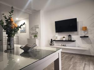 a white living room with a television and a chair at Los Titos in Arriate