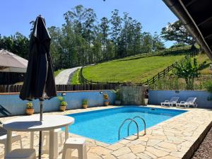 a swimming pool with a table and an umbrella at Paraíso Pomerode in Pomerode