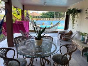 a glass table and chairs on a patio with a pool at Paraíso Pomerode in Pomerode