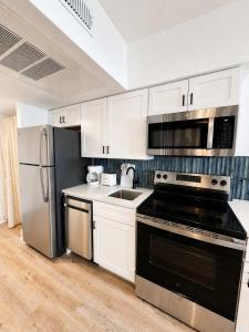 a kitchen with white cabinets and a black appliance at Boardwalk Noir - Oceanfront Studio Yachtsman 404 in Myrtle Beach