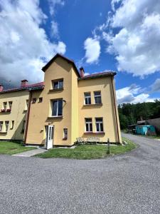 a yellow house on the side of a road at Apartmán Líšný - U Jizery in Líšný