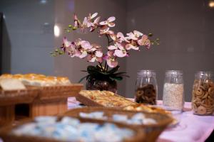 a table with pastries and a vase with pink flowers at Manacá Hotel in Foz do Iguaçu