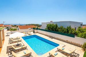 a swimming pool on the roof of a house with lounge chairs at Villa Ingrid Porter by Villa Plus in Cala en Porter