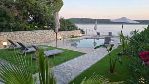a backyard with a swimming pool and a stone wall at OlivaBeachHouse - Direct Waterfront & Mooring in Barbat na Rabu