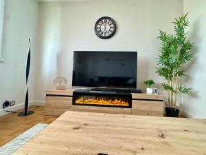 a living room with a fireplace and a clock on the wall at Le petit sauna de Sarah in Voiron