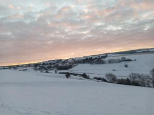 a field covered in snow with the sunset in the background at Ferienwohnung Otto in Kleinich +10 photos