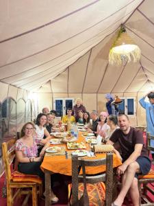 a group of people sitting at a table in a tent at Riad Kasbah Le Touareg in Merzouga