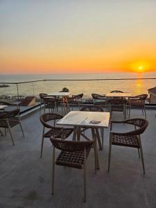 a group of tables and chairs with the sunset in the background at Bedo Boutique Hotel in Golem +16 photos