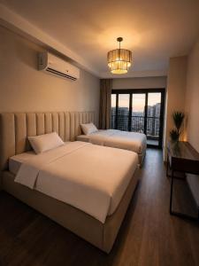 two beds in a hotel room with a large window at ZED Towers City View Apartment in Sheikh Zayed