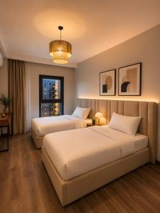 a hotel room with two beds and a window at ZED Towers City View Apartment in Sheikh Zayed