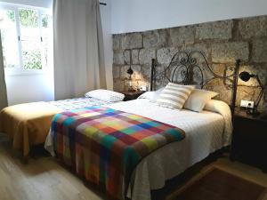 1 dormitorio con cama y pared de piedra en Finca El Trazo, en Tacoronte