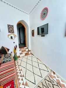 a living room with a couch and a tv on the wall at Dar Zagora Oasis - Authentic Moroccan Stay in Zagora