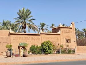 a brick building with palm trees in the background at Dar Zagora Oasis - Authentic Moroccan Stay in Zagora