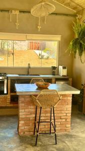 a kitchen with a counter with two chairs and a table at EcoRefúgio Verde - iUna in Ibiúna