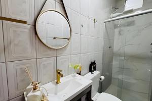 a bathroom with a sink and a mirror and a toilet at Abaíra Serra Azul Suítes 02 - Centro in Petrolina