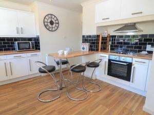 a kitchen with white cabinets and a table and stools at Bayview Cottage in Bournemouth +14 photos