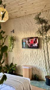 a tv hanging on a wall in a room with plants at EcoRefúgio Verde - iUna in Ibiúna