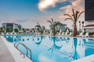 a large swimming pool with chairs and palm trees at Graf Victor Hotel - All Inclusive Non Alcoholic Drinks in Çamyolu +12 photos