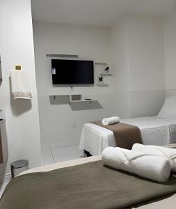 a white room with two beds and a flat screen tv at Abaíra Serra Azul Lofts 1 - Orla - Centro in Petrolina