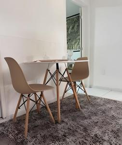 a dining room table with two chairs on a rug at Abaíra Serra Azul Lofts 1 - Orla - Centro in Petrolina +11 photos