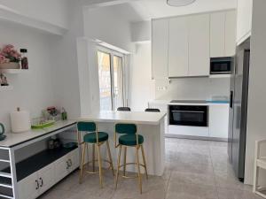a kitchen with white cabinets and green bar stools at Piraeus new hotel in Piraeus