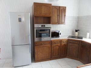 a kitchen with a white refrigerator and wooden cabinets at Gite des galets in Saint-Léonard
