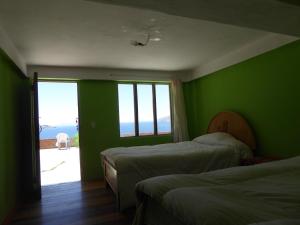a green room with two beds and a window at Ecolodge Amanecer in Comunidad Yumani