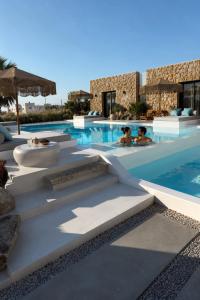a pool at a resort with people in the water at Myconian Theros Luxury Suites in Ano Mera