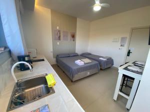 a small room with two beds and a sink at Hotel kitnet Digital in Passos
