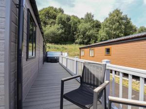a black chair sitting on a wooden deck at Cedar Lodge 2 Bedrooms with hot tub in Northwich