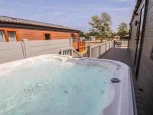 a hot tub on the deck of a house at Cedar Lodge 2 Bedrooms with hot tub in Northwich +7 photos