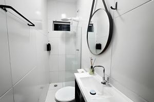 a white bathroom with a sink and a mirror at Abaíra Serra Azul Loft 6 - Orla - Centro in Petrolina